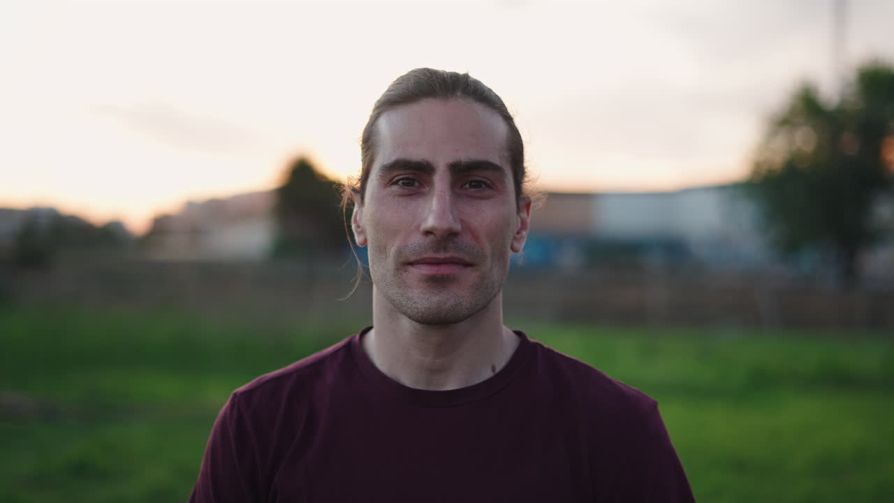 Young Man Smiling at Camera Outdoors During Sunset