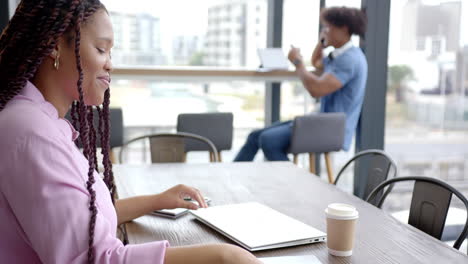 reviewing documents, woman sitting at table with laptop and coffee in office