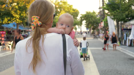 young mother with baby daughter strolling in the city street