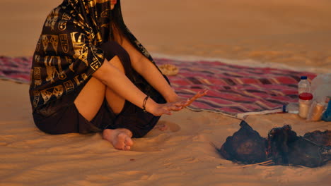 mujer calentando las manos junto a una fogata en el desierto del sáhara