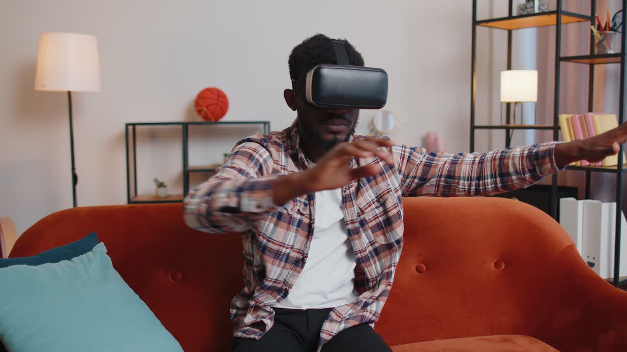Young man use virtual reality headset glasses at home enjoying video concept moving hands in air