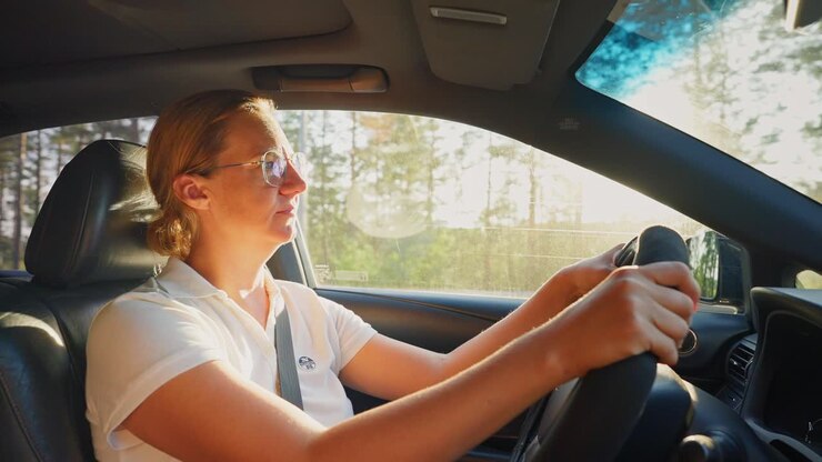 Donna che guida un'auto in una giornata di sole