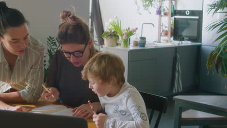 lesbian parents doing homework with little son