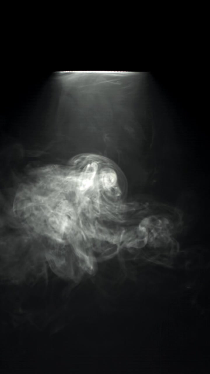 Fumo bianco misterioso che si diffonde sotto un riflettore su sfondo nero