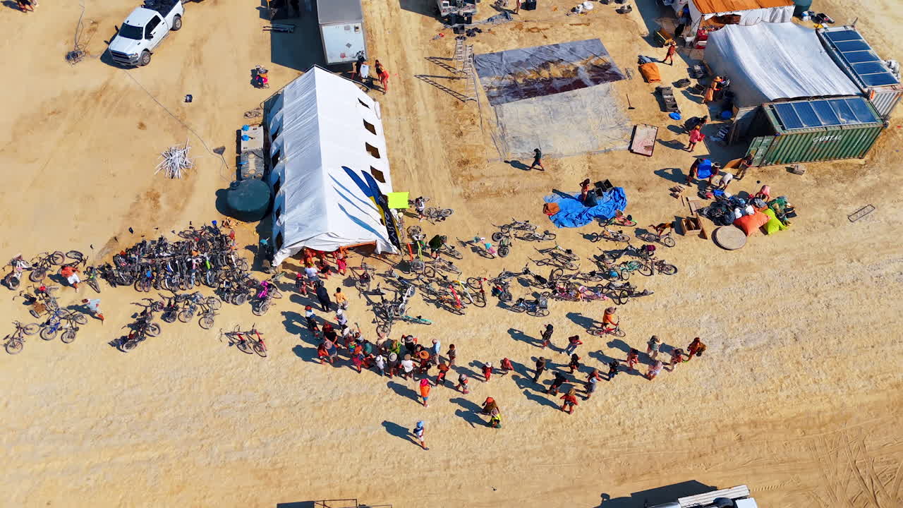 Nevada, USA, 25 August 2025: Drone shot of participants and bicycles gathered around a large white tent during the Burning Man festival