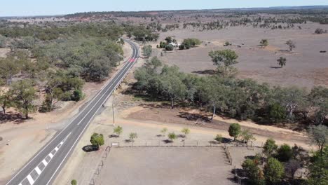 Luftaufnahme-Eines-Buschlandes-Und-Einer-Asphaltierten-Straße-Sowie-Einer-Unbefestigten-Straße-Im-Australischen-Outback