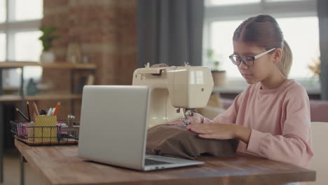 una joven aprendiendo a coser en una máquina de coser.