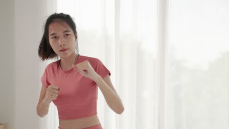 slow motion footage shot of beautiful asian woman doing exercise round boxing in the room.