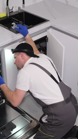 a man installs a new dishwasher in the kitchen room vertical video