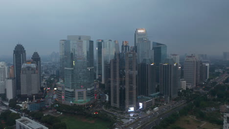 Aerial-truck-evening-view-of-modern-skyscraper-complex-by-a-busy-multi-lane-highway-in-Jakarta