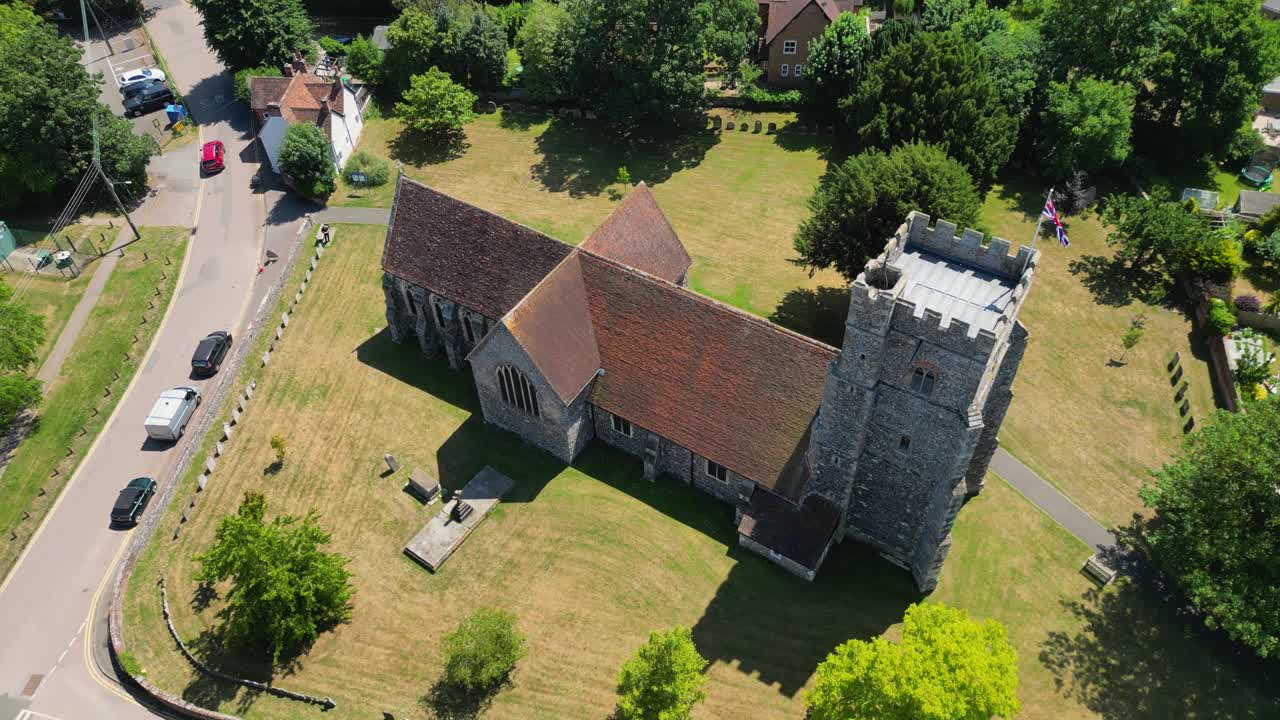An arc-shot of St Mary's church, arcing around the church and showing the surrounding greenery and union flag flying from the tower