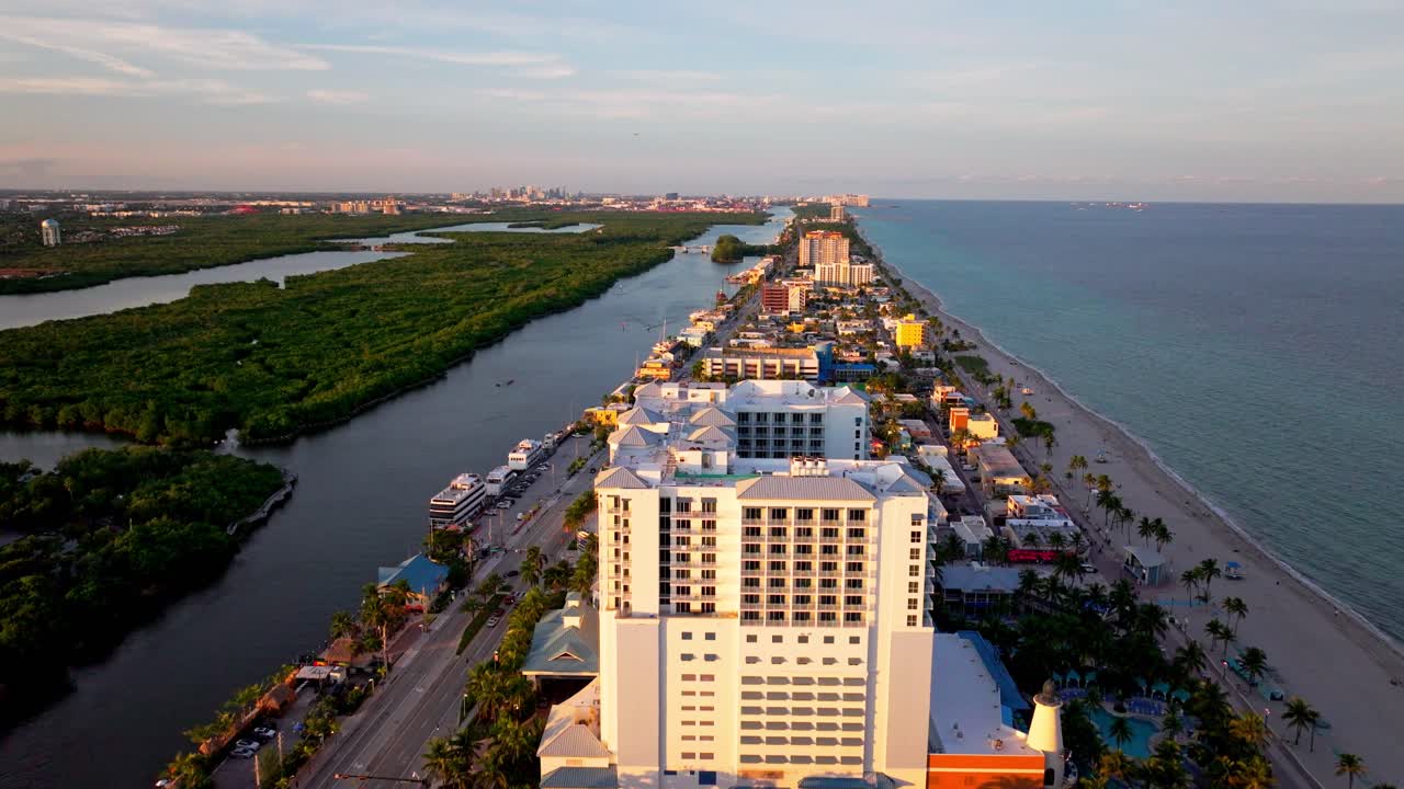 High-resolution aerial footage overlooking Hallandale Beach, Florida. Featuring coastal residential buildings, beachfront roadway, inland waterways, and the Atlantic Ocean's shoreline
