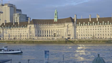 Boat-navigating-along-River-Thames-with-County-Hall-in-background,-London