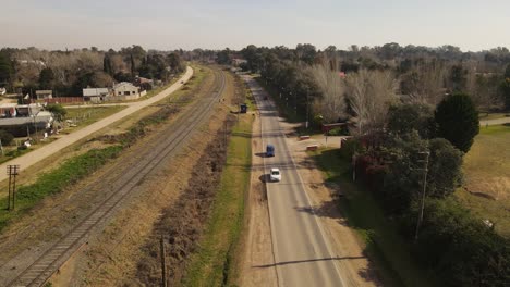 aerial shot of cars driving on rural road in suburb area of buenos aires during summertime - tilt down 4k shot