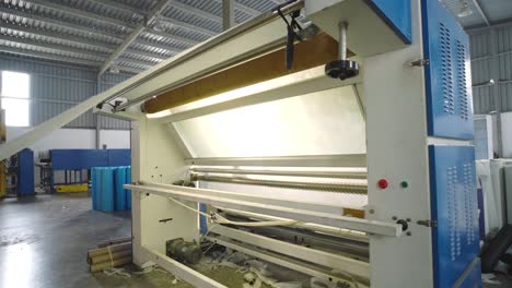 white textile fabric being fed into textile machine in warehouse