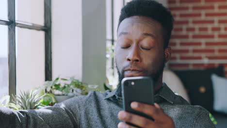 Phone,-coffee-and-black-man-relaxing-in-his-living