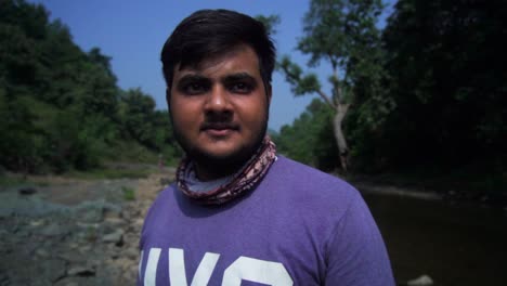 young man by a river in a forest