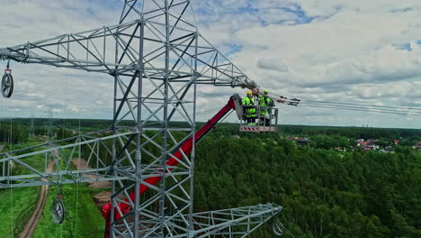 Close-up-shot-of-workers-installating-power-line-pylon-using-construction-equipment-over-a-newly-installed-on-electric-pole-on-a-cloudy-day