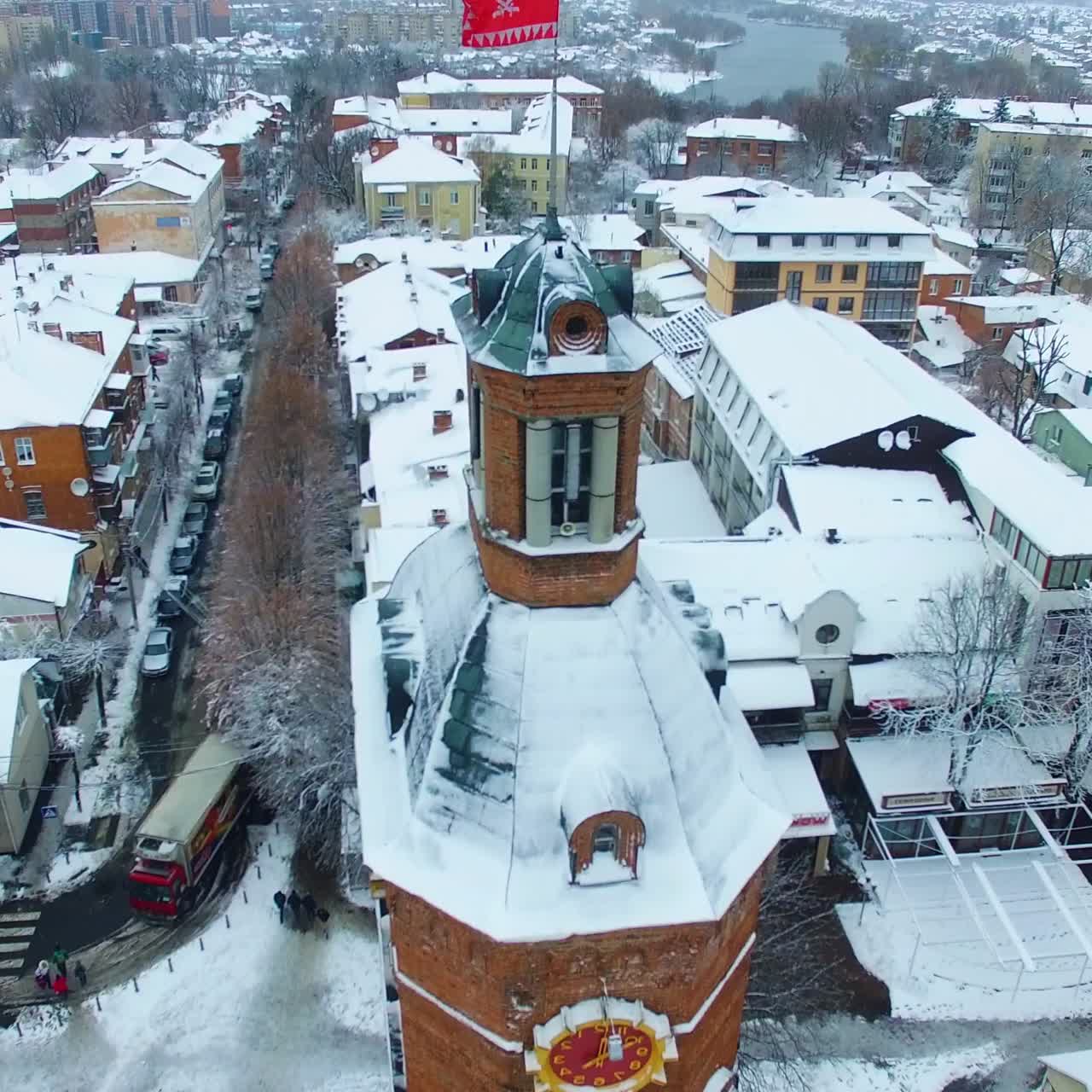 Historic building of old water tower with clock in Vinnytsia, Ukraine. Snow-covered roofs of the city in winter. Aerial view