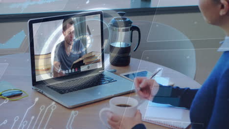 person holding mug watching video call on laptop with digital overlay animation