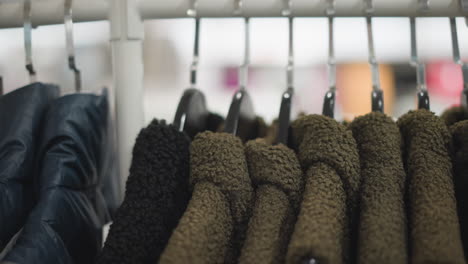 close-up of neatly arranged jackets in varying shades, including textured wool and sleek leather designs, displayed on hangers in a well-lit retail store