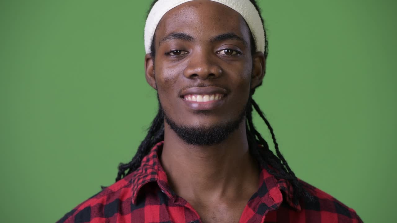 joven hombre africano guapo con dreadlocks contra un fondo verde