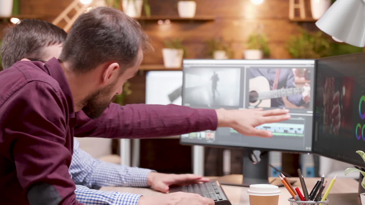 Two men collaborating on a video editing project in an office
