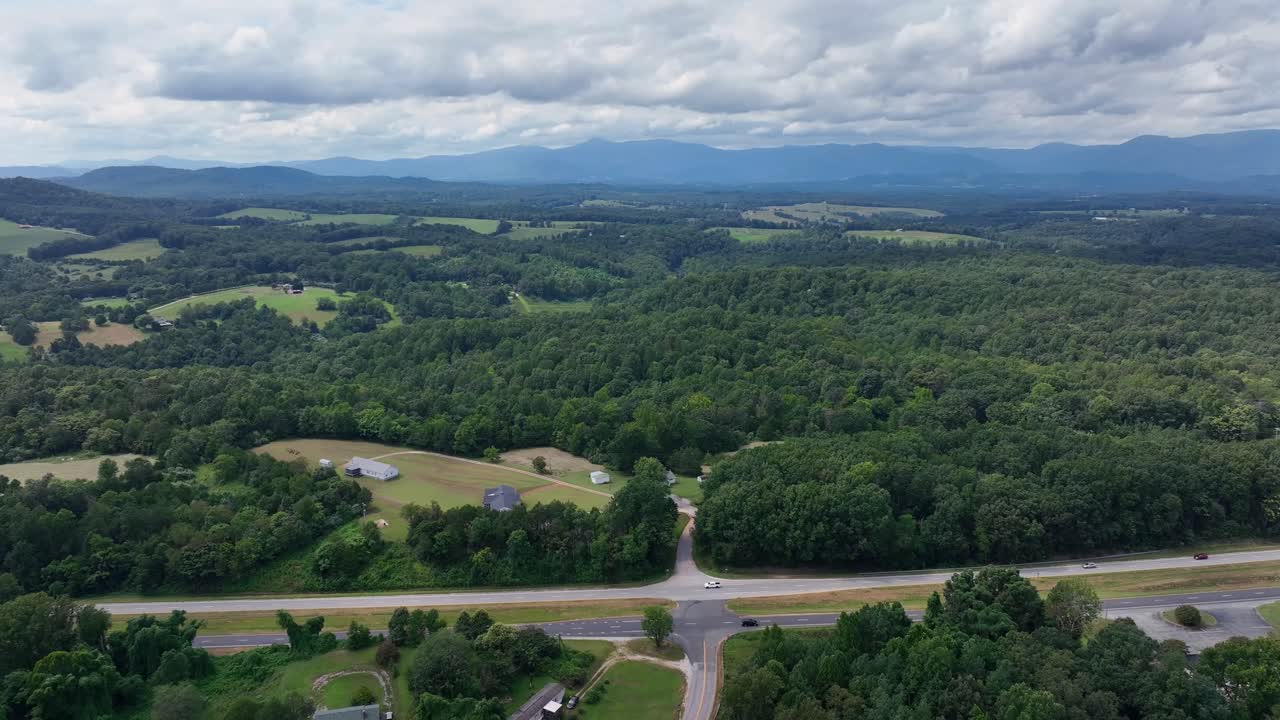 Virginia landscape with forest trees, cars on highway and suburb neighborhood with large properties. Descend drone panorama. Cloudy summer day in United States. Film scene in rural area