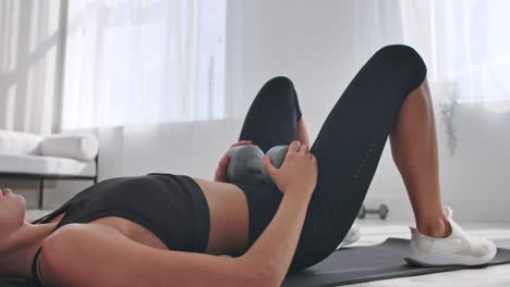 Portrait-of-young-motivated-athletic-female-making-pelvis-lifting-with-weights-indoors