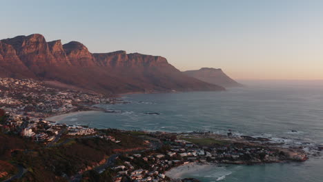 sunset drone shot of camps bay in cape town, south africa