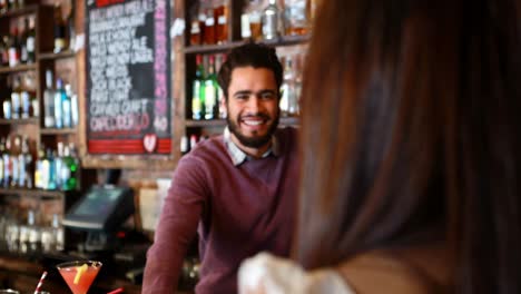 barman interactuando con la mujer cliente en el mostrador de la barra
