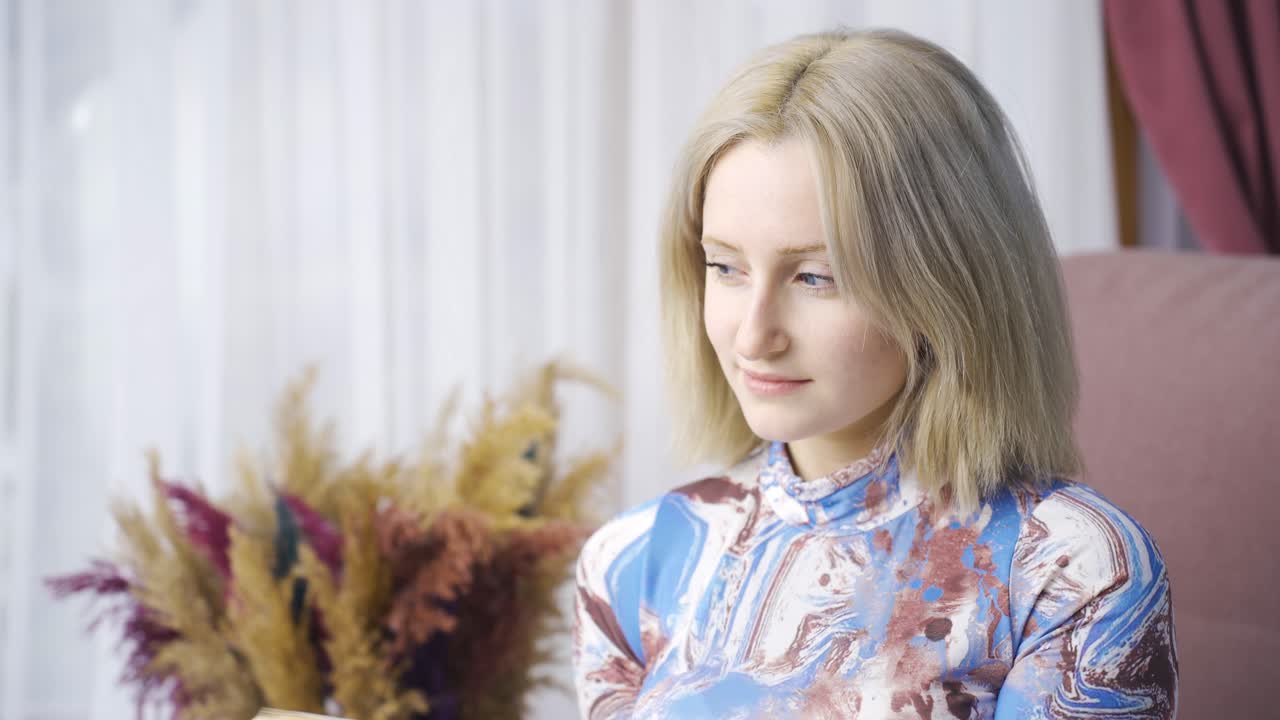 행복한 여성이 집에서 책을 읽고, 아름답게 생각하고, 꿈을 꾸고 있습니다.