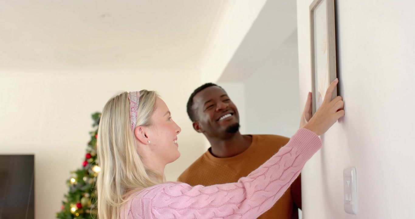 Femme entrant avec un cadre et son partenaire la soutenant, tandis que des graphiques rouges suivent le nivellement dans la décoration intérieure