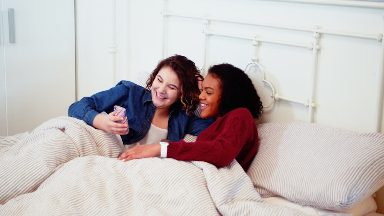 pareja de lesbianas usando el teléfono móvil en la cama