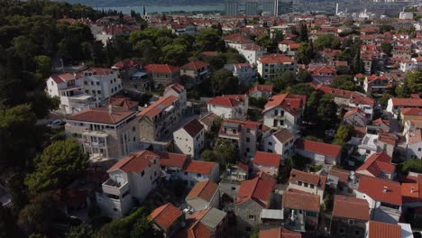 Toma-Aérea-Inclinada-De-Los-Hermosos-Tejados-Tradicionales-De-Split,-Croacia,-Abrazados-Por-El-Hermoso-Parque-Suma-Marjan,-En-La-Costa-Del-Mar-Adriático