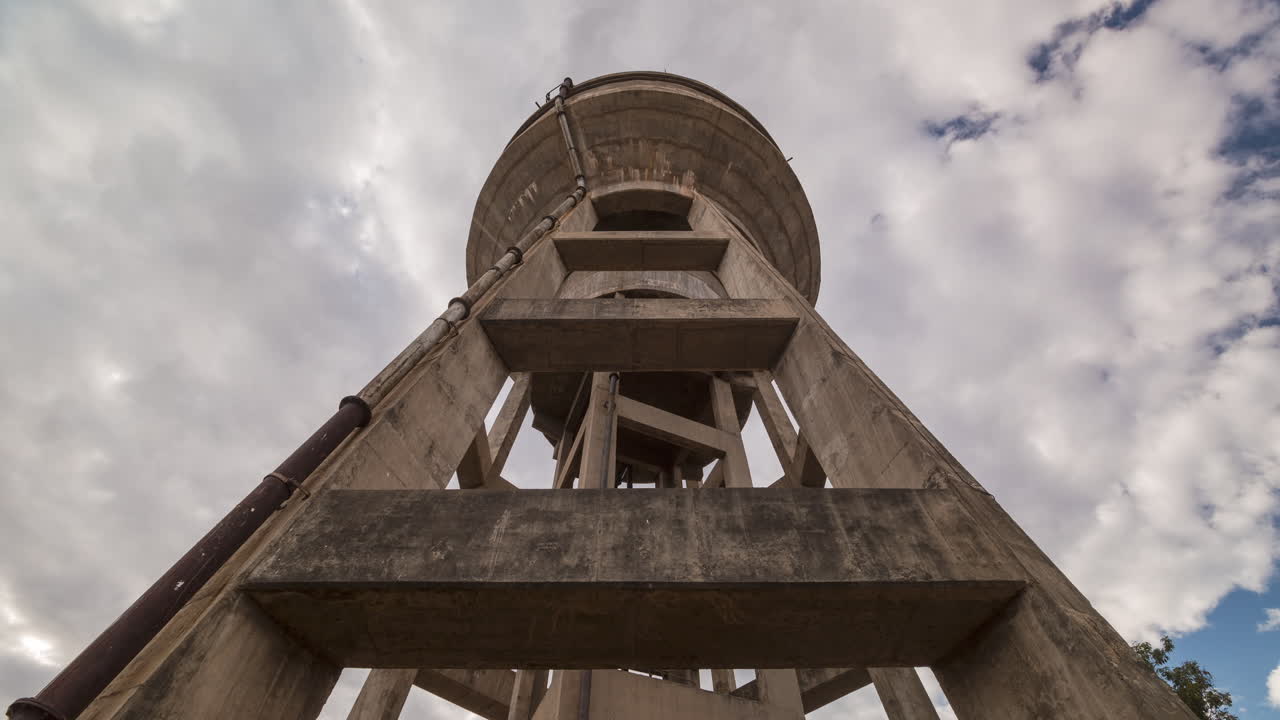 Time-lapse of a large water tower in Africa, looking up towards the sky with clouds and slow camera movement