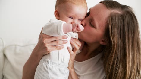 cheerful mom kissing cute baby daughter