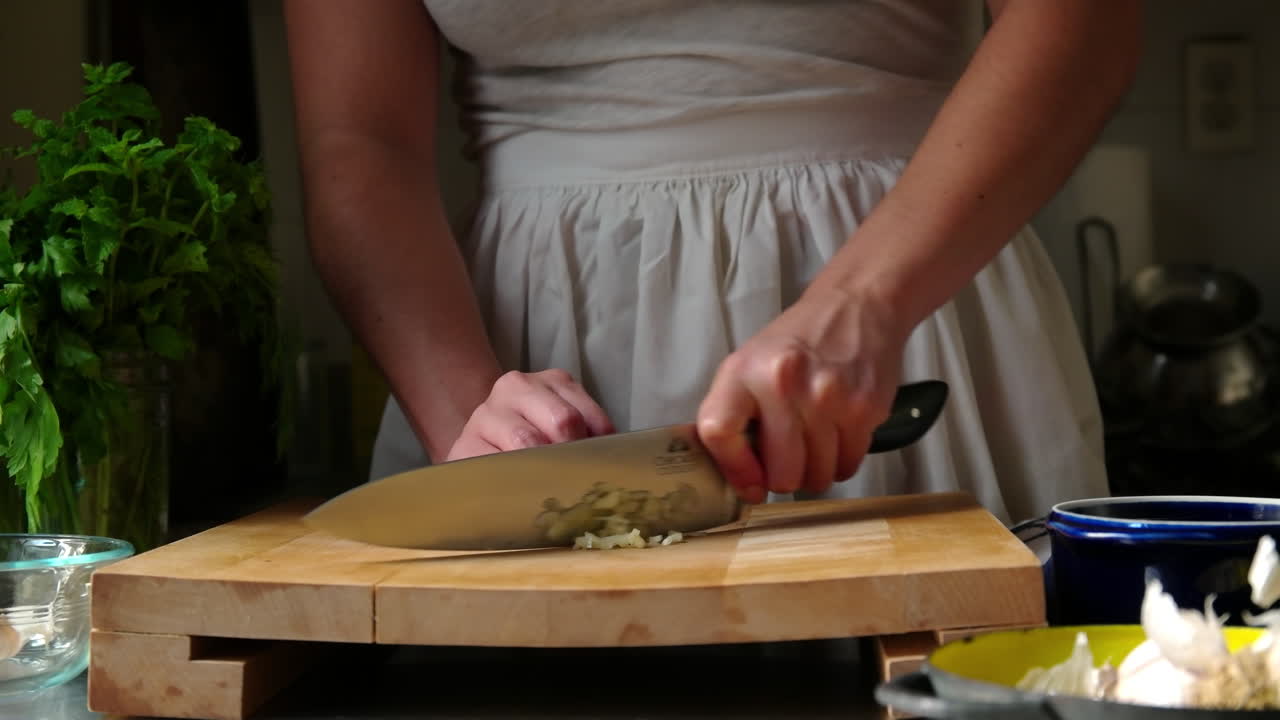 Donna trita l'aglio su un tagliere