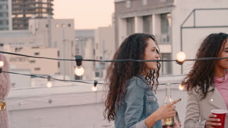 group of happy friends hanging out dancing together enjoying rooftop party at sunset drinking having fun on weekend celebration