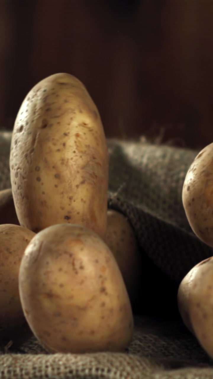 Patate crude che cadono su un sacco di iuta al rallentatore