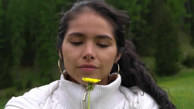 Donna felice con occhi profondi che tiene un dente di leone giallo, vista ritratto.