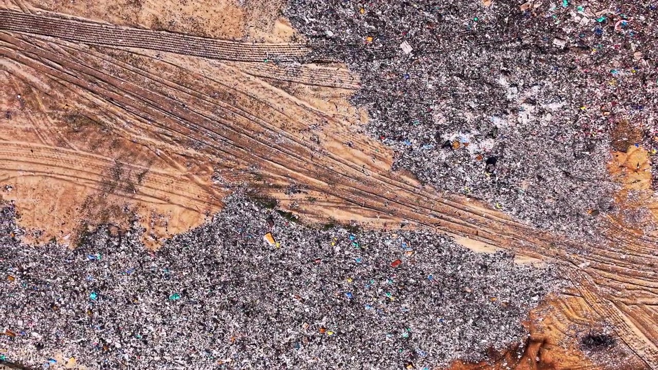 Vista aérea de detritos plásticos cortados por trilhas de terra marrom feitas por caminhões pesados. Textura aérea de uma pilha de lixo doméstico misto com estradas de terra.