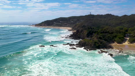 Wide-drone-shot-of-ocean-and-island-in-background-at-Wategos-Beach-in-Byron-Bay,-Australia