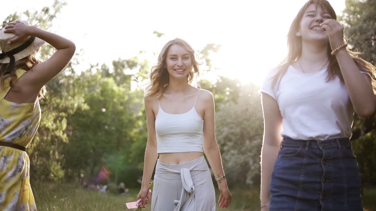 tres hermosas chicas en una despedida de soltera en la naturaleza. caminando en el verde bosque de verano. riendo, saltando libremente. cámara lenta