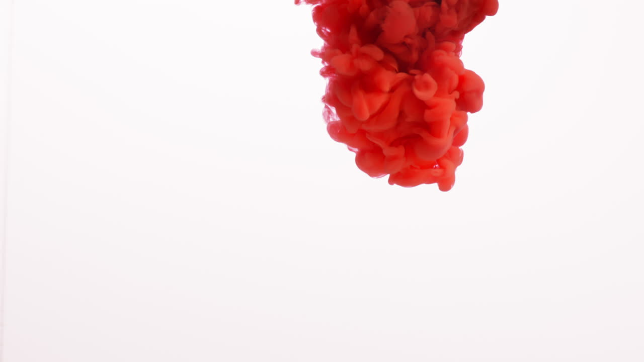 pintura o tinte naranja derramada en agua contra un fondo blanco para crear un fondo de humo de colores giratorios 2