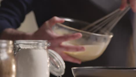 close-up do homem na cozinha assando em casa mexendo os ingredientes na tigela e despejando na forma de bolo