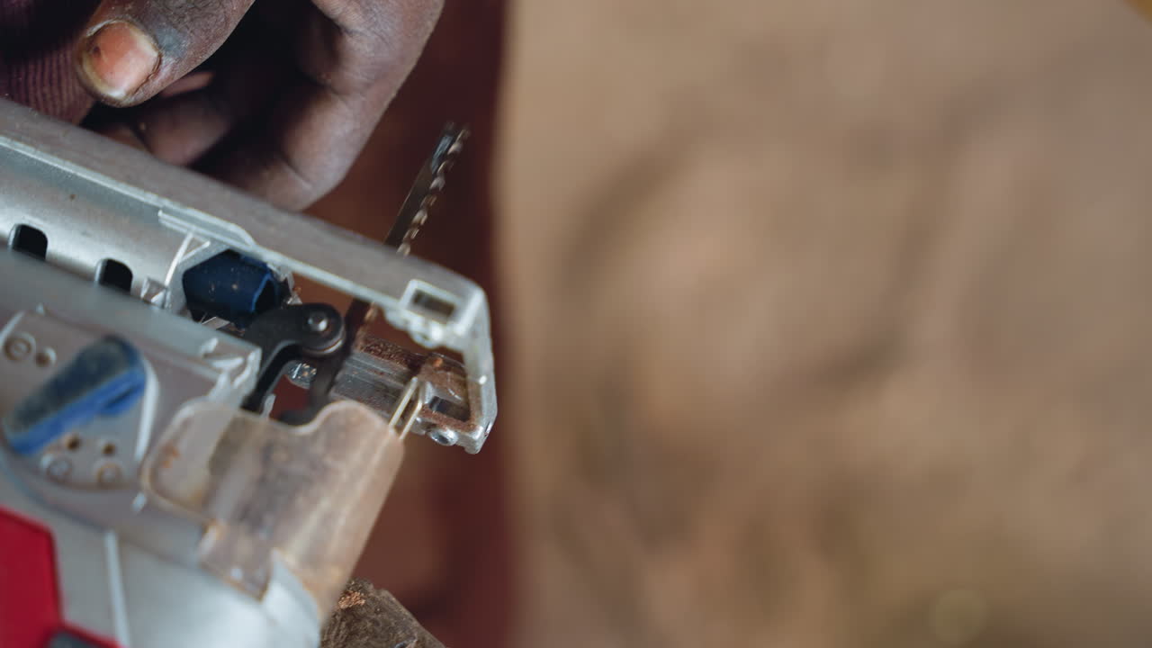 Mani che maneggiano un seghetto alternativo. Operaio che taglia abilmente il legno con un seghetto alternativo tra polvere e concentrazione. Artigiano esperto che aziona un seghetto alternativo durante un progetto meticoloso in un cantiere polveroso