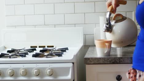 woman pouring water into mug from kettle 4k