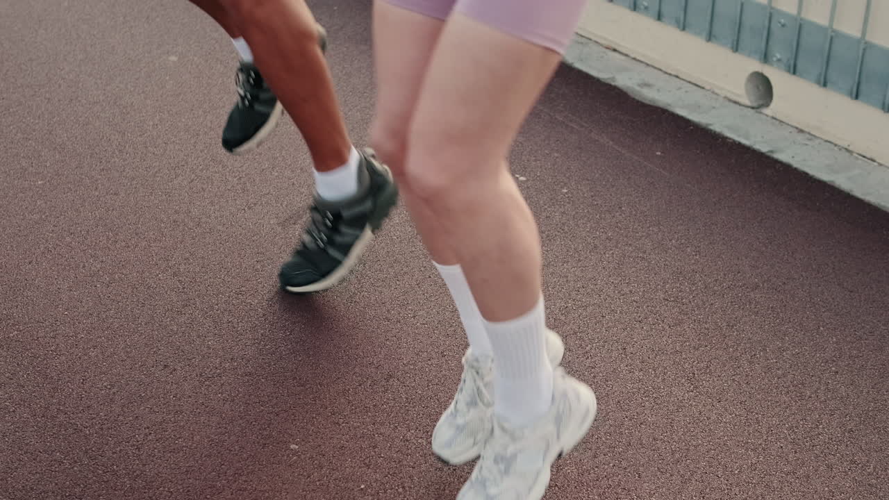 Close-up of Two People's Legs Jogging on an Outdoor Track