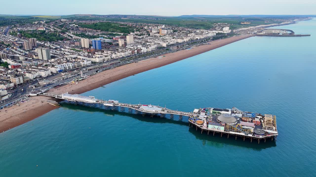 Beautiful aerial footage of Brighton's iconic pier. Calm sea, busy beach, marina and white cliffs can be seen in background. Ideal for Brighton event marketing, tourism and summer day media.